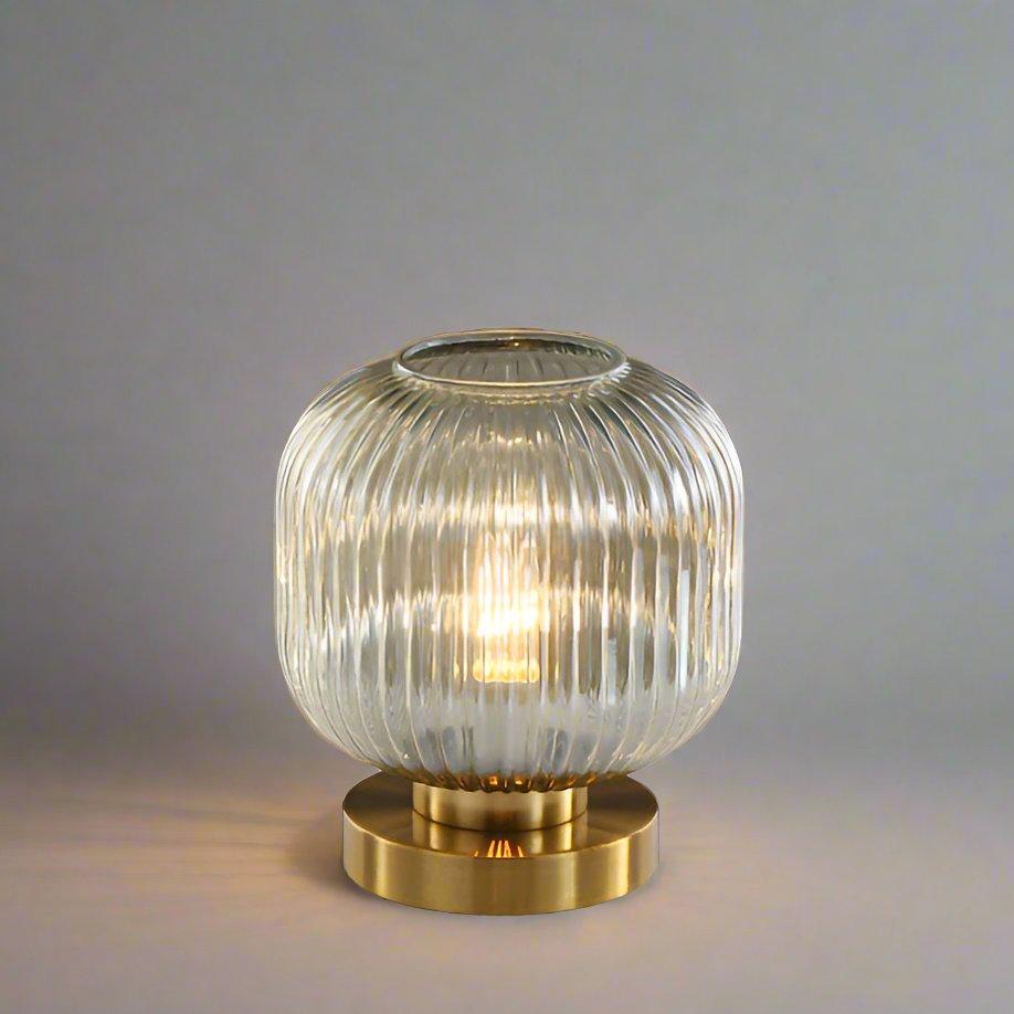Bordlampe i ravfarvet glas med minimalistisk metalstel og varmt stemningslys