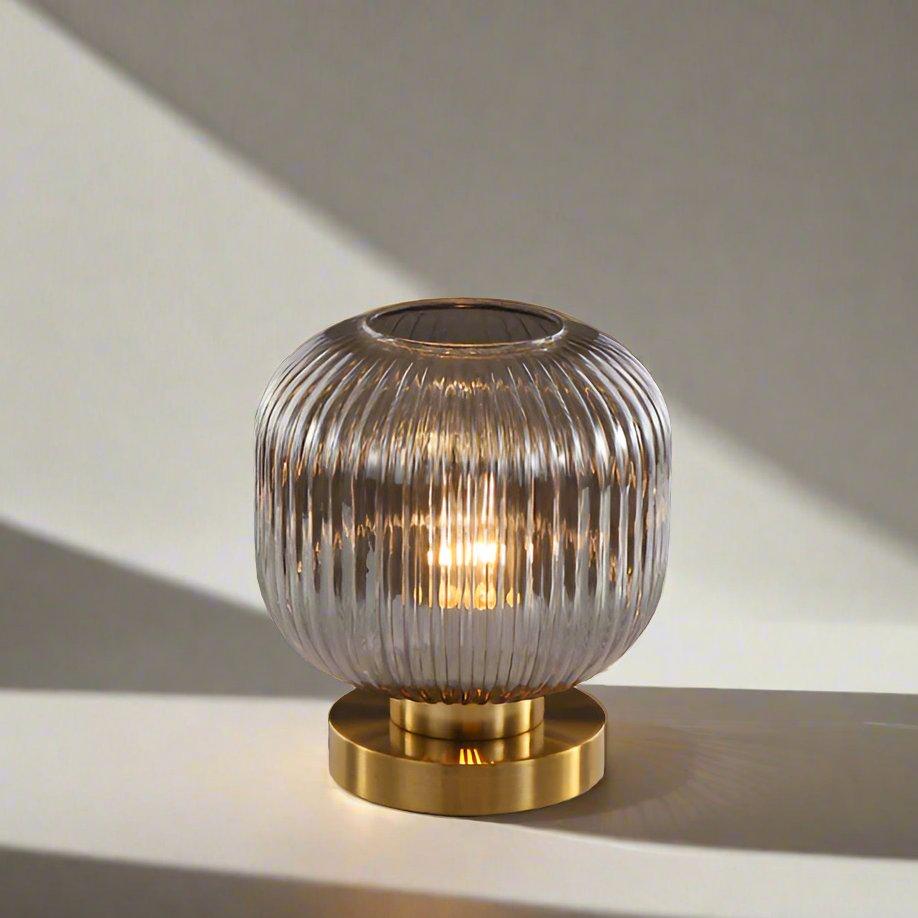 Bordlampe i ravfarvet glas med minimalistisk metalstel og varmt stemningslys