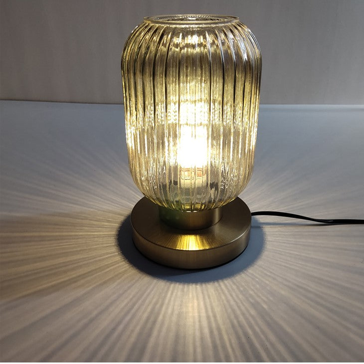 Bordlampe i ravfarvet glas med minimalistisk metalstel og varmt stemningslys