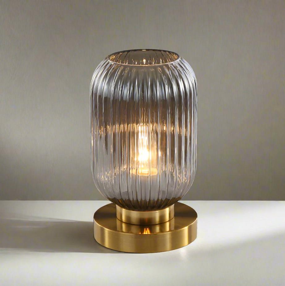 Bordlampe i ravfarvet glas med minimalistisk metalstel og varmt stemningslys