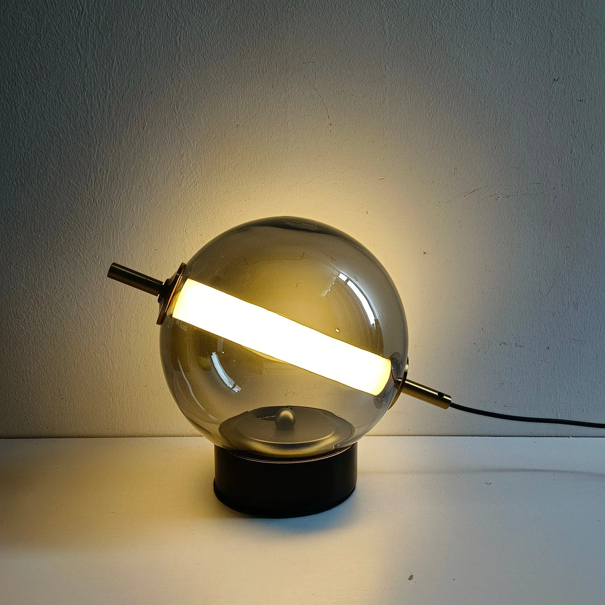 Elegant bordlampe med kugleformet matteret glasskærm og metalfod